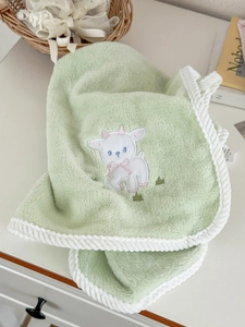 Detail of light green lamb coral fleece towel with white rope edges and soft embroidery