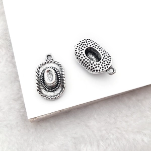 Detailed view of vintage silver cowboy hat pendant with textured alloy finish on plush background