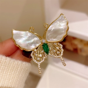 Golden butterfly brooch with natural shell wings and emerald green stone inlay