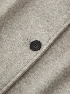 Close-up of beige wool coat fabric showing fine texture and dark brown button detail