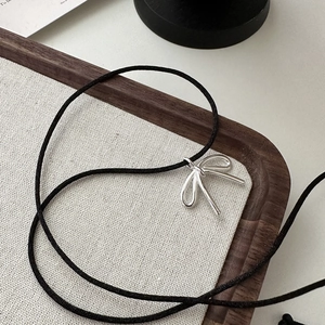 Elegant S925 sterling silver bow pendant necklace with adjustable black cord on fabric
