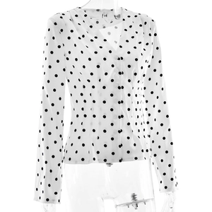 Detail view of the V-neckline and black polka dot pattern on the white long-sleeve blouse