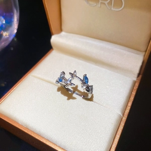 Detailed macro view of a silver flower ring with blue zircon stones on a beige gift box
