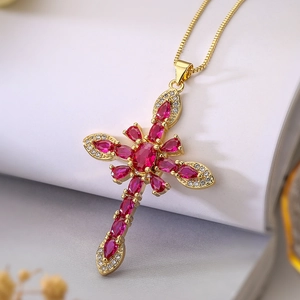 Macro shot of 18K gold plated necklace with ruby-colored cross pendant and white zirconias