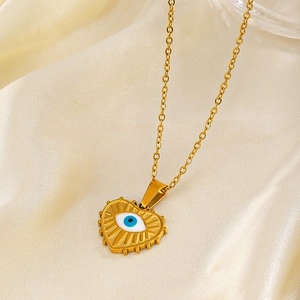 Golden heart necklace with evil eye charm on soft silk background, vintage style jewelry