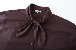 Detail of dark brown cotton poplin shirt showing the bow-tie neckline and button craftsmanship