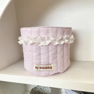 Macro shot of pink striped quilted storage basket with lace trim and fabric brand label