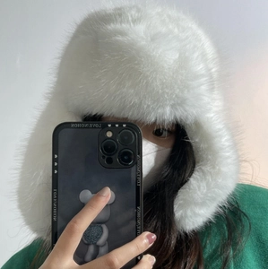 Dettaglio del cappello da aviatore in finta pelliccia bianca mostrato nel selfie