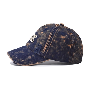 Close-up of distressed acid wash denim baseball cap with embroidered letter K and frayed details