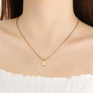 Close-up of gold box chain necklace with letter M square pendant on model's neck