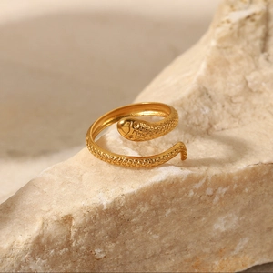 Macro shot of a vintage gold-plated snake ring with diamond accents on a natural stone
