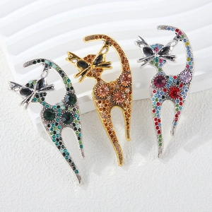 Detailed view of three cat brooches with colorful rhinestones on a textured background
