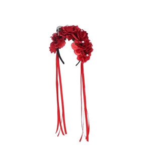 Detail of Halloween headband with red roses, skull charm, and long red ribbons on white backdrop