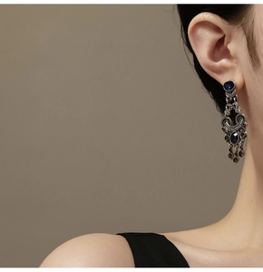 Detail of vintage silver fringe earrings with blue gemstones on elegant model