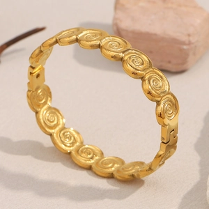 18K gold-plated stainless steel bangle with spiral pattern on textured background