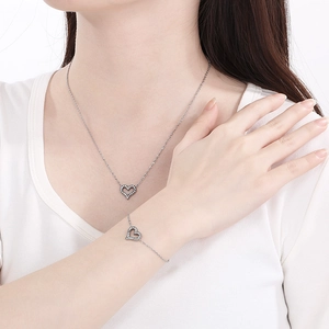 Close-up of silver hollow heart necklace and bracelet set with inlaid sparkling micro diamonds