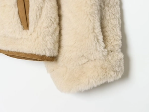Détail de la veste en polaire crème avec bordure marron montrant la texture du tissu