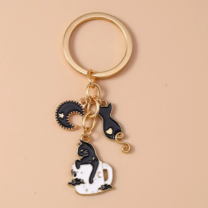 Detail of golden keychain featuring enamel black cat silhouette and crescent moon charms