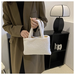 Close-up of fluffy white faux fur tote bag held by model in brown blazer