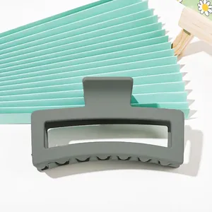Close-up of a matte sage green rectangular hair claw clip with a secure grip design