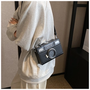 Detail of a vintage camera-shaped crossbody bag with a chain strap and PU leather texture