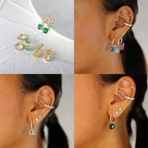 Detailed view of gold earrings with colorful gemstones and matching ear cuffs on model