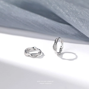 Macro shot of S925 sterling silver hoop earrings with diamond-set twisted wave patterns