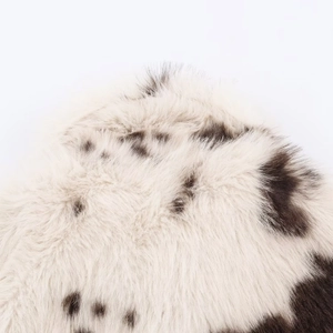 Gros plan sur le tissu en fausse fourrure blanche à taches noires d'une veste mode
