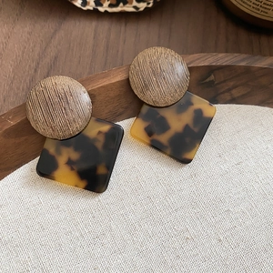 Macro detail of vintage geometric earrings with brown wood and tortoise shell patterns