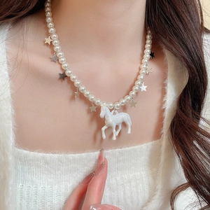 Détail des charms cheval et étoile sur un collier de perles porté par un mannequin
