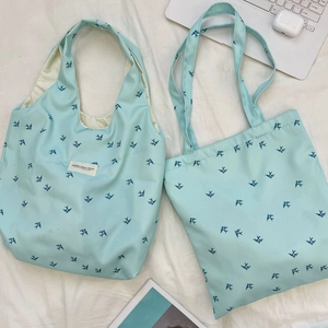 Flat lay of two blue canvas tote bags with swallow prints and studio brand label