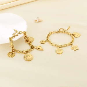 Detail of gold beach bracelets with wave and seashell charms on beige silk texture