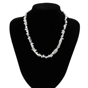 Detailed view of silver irregular metal bead necklace on a black velvet mannequin