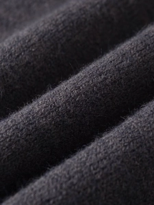 Détail macro d'un tricot gris foncé montrant la texture douce et la maille de laine