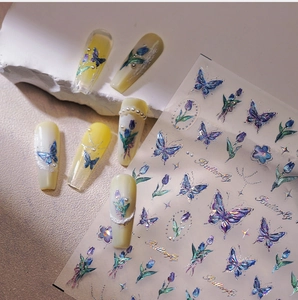 Macro detail of holographic blue butterfly and tulip nail decals with metallic finish