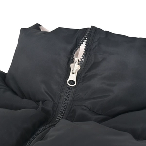 Detail of silver metal zipper and quilted texture on a black padded puffer vest