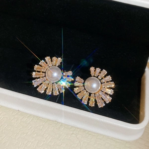 Detailed view of gold plated fan shaped earrings with white pearls and clear zircons