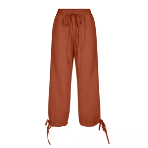 Detail view of cotton linen drawstring waist and tied cuffs on rust red casual trousers