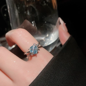 Macro shot of silver crisscross ring with light blue gemstone and shimmering accents