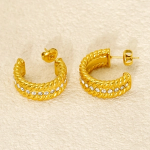 Detail of gold C-hoop earrings with twisted cable texture and inlaid white zircons