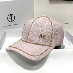 Pink tweed baseball cap featuring rhinestone edge trim and gold metal M logo detail