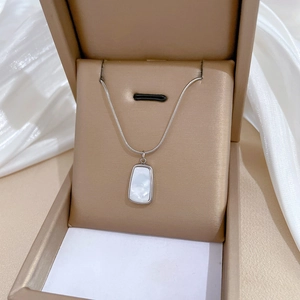 Close-up of silver snake chain necklace with shell pendant in a premium gift box