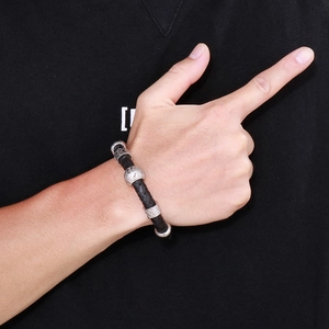 Gros plan d'un bracelet en cuir tressé noir avec des perles argentées au motif vintage