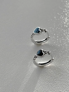 Macro shot of silver rope twist heart earrings with black enamel inlay on white texture