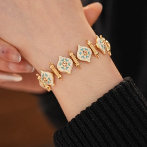 Close-up of vintage gold bracelet with blue and white enamel rhombuses and small rhinestones