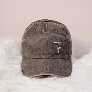 Detailed view of white Faith embroidery and cross on washed grey cotton baseball cap