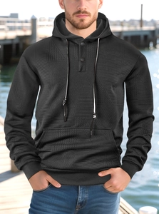 Detailed macro shot of men's black knit hoodie featuring geometric textured fabric and buttons