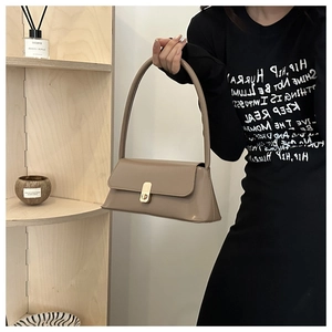 Detail of khaki PU leather shoulder bag with golden square metal buckle on a model