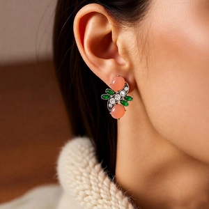 Close-up of vintage resin pink oval earrings with green leaf gems worn by a model