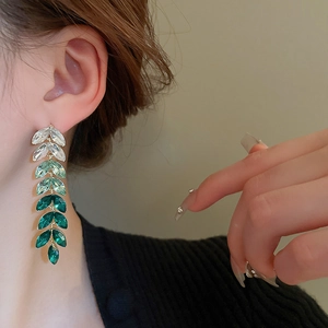 Close-up of long tassel earrings with gradient emerald green marquise-cut crystals